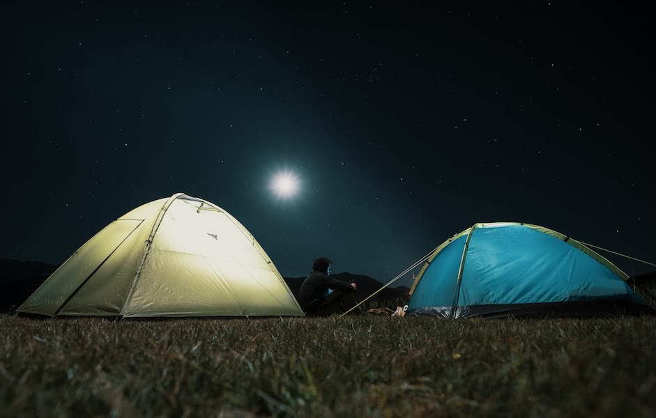Camping tents lit up at night — kit completeness ready for trips