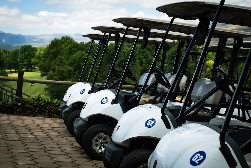 Row of golf carts at a resort with one being handed over to guests