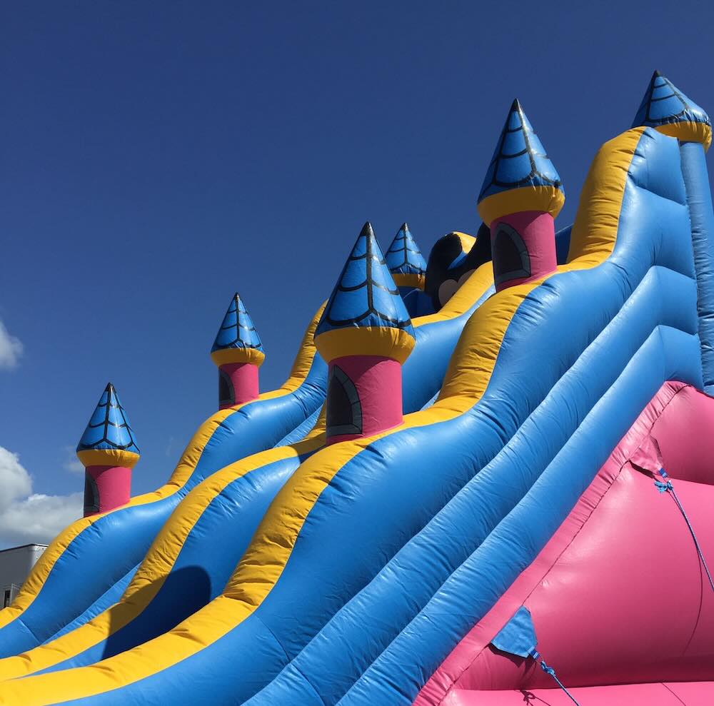 Bounce house being set up on grass with a blower running